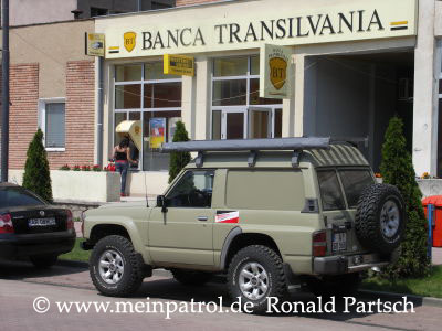 Fumosito und der Held vor der Banca Transilvania Transsylvania in Sebis Rum&auml;nien Nissan, nissan, Patrol, patrol, Safari, safari, Patrol GR, patrol gr, Safari GR, safari gr, GR, gr, KR, kr, Patrol GQ, patrol gq, Safari GQ, safari gq, GQ, gq, Y60, y60, JRY60, jry60, JRLY60, jrly60, VRGY60, vrgy60, ARGY60, argy60, TD42, td42, 4.2-Liter, 4.2 Litre, 4.2 litre, 4,2-Liter, Sechszylinder, Inlinesix, inlinesix, high roof, Hochdach, Jeep, jeep, Wrangler, wrangler, TJ, tj, Yamaha, Kodiak, yamaha, kodiak, 4x4, 4WD, 4wd, four wheel drive, AWD, awd, Offroad, offroad, Off Road, OFF ROAD, off road, offroader, Allradler, Allradantrieb, Gel&auml;ndeuntersetzung, Reduktion, low gears, Differenzialsperre, Differentialsperre, locker, Gelaendewagen, Gel&auml;ndewagen, Reisen, reisen, travel, Expedition, expedition, Tour, tour, Tuning, tuning, tune, Zubeh&ouml;r, equipment